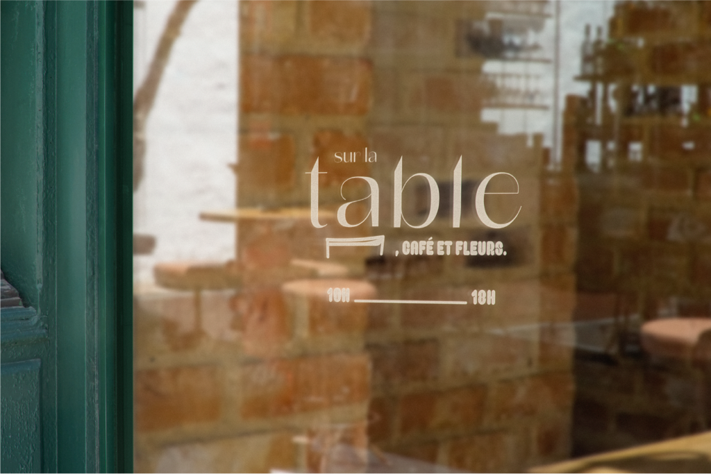 Porte vitrée du café-fleuriste Sur la table avec le logo dessus